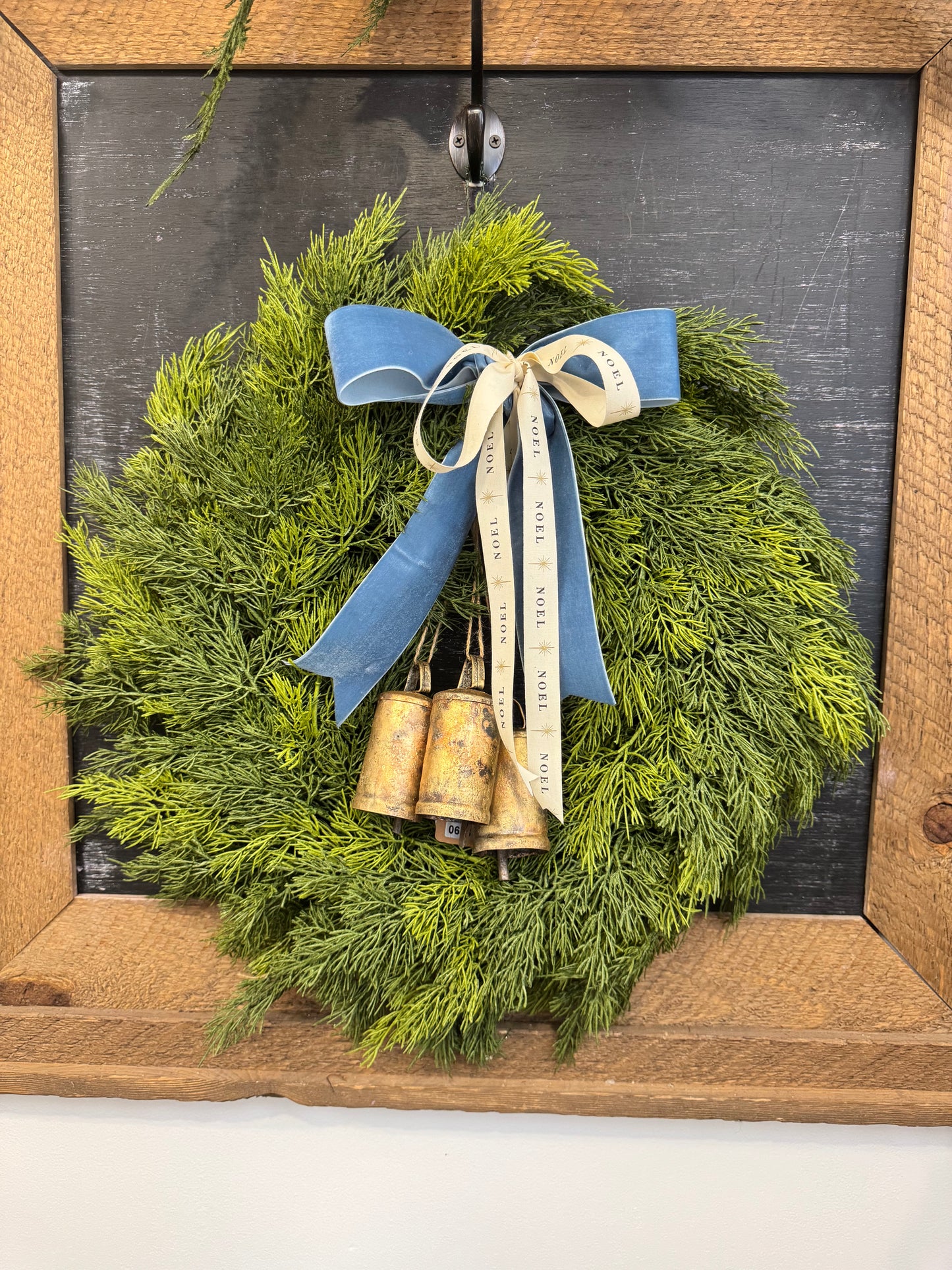 “Noel” Cedar wreath with brass bells and layered bow
